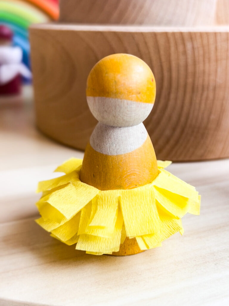 Yellow peg doll with paper skirt